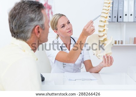 Doctor showing her patient a spine model in medical office
