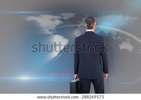 Businessman in suit holding a briefcase against glowing world map on black background