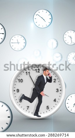 Businessman running on the phone against digitally generated floating clock pattern