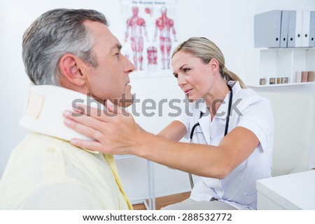 Doctor examining patient wearing neck brace in medical office