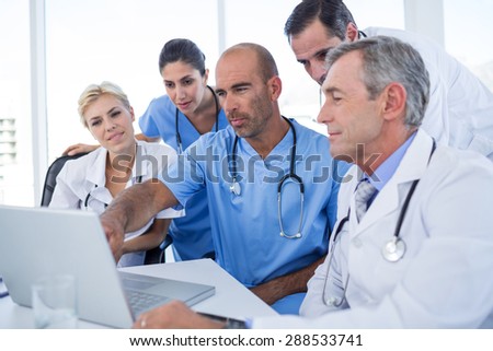 Doctor showing laptop pc to his colleagues in medical office