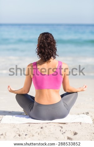 Wear view of fit woman doing yoga beside the sea at the beach