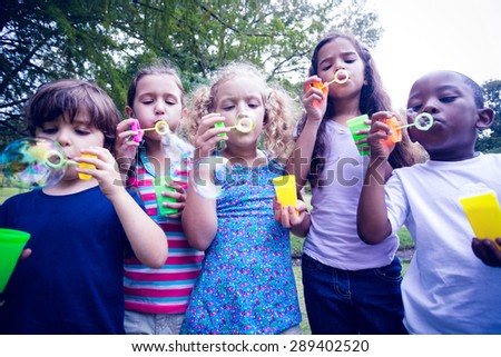 Children playing with bubble wand in the park on a sunny day