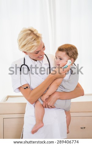 Smiling blonde doctor with child and stethoscope in the medical office