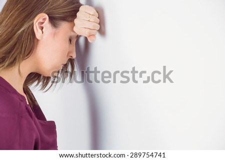 Depressed man leaning her head against a wall on white background