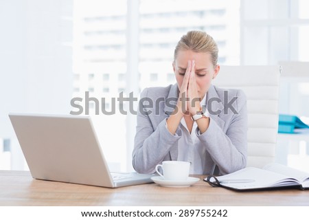 Frustrated businesswoman with head in hands in her office