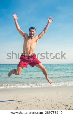 Happy man jumping on the beach on a sunny day