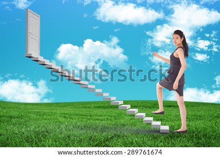 Businesswoman stepping up against green field under blue sky