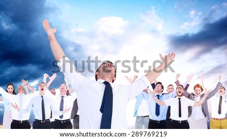 Handsome businessman cheering with arms up against cloudy sky