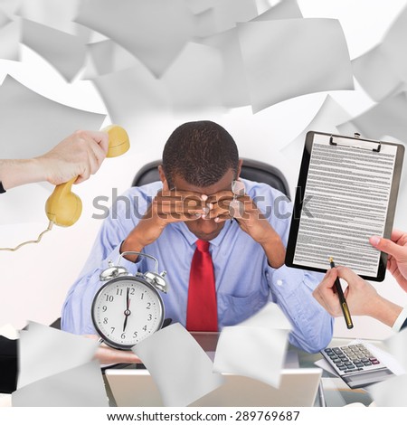 hand holding phone against frustrated afro businessman with head in hands at desk
