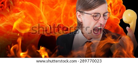 Geeky businessman shouting at retro phone against fire