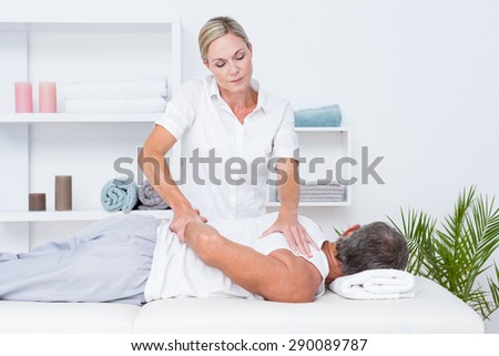 Physiotherapist doing shoulder massage to her patient in medical office