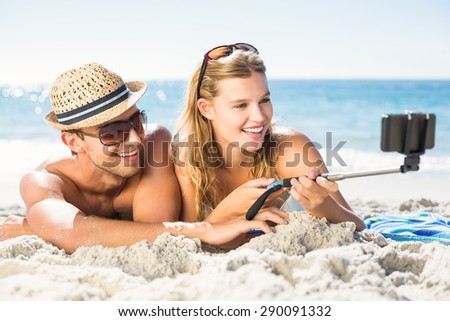 Happy couple taking selfie with selfie stick at the beach