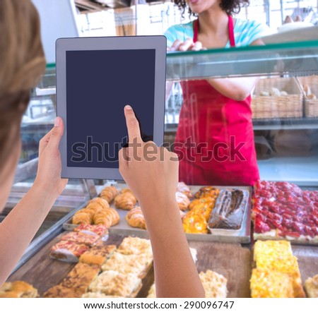 Woman using tablet pc against happy waitress using laptop on counter