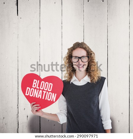Geeky hipster holding heart card against white wood