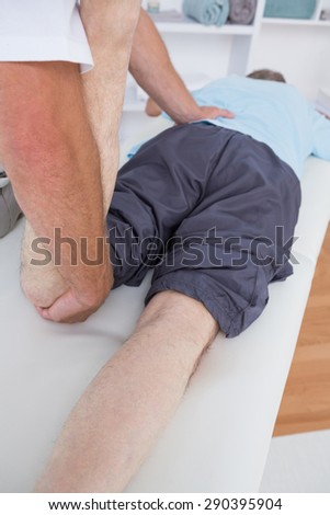 Physiotherapist doing leg massage to his patient in medical office