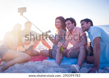Happy hipsters taking pictures with selfie stick at the beach