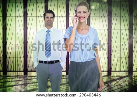 Businesswoman having phone call while her colleague posing against window overlooking city