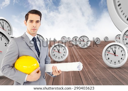 Serious architect holding plans and hard hat against cloudy sky background