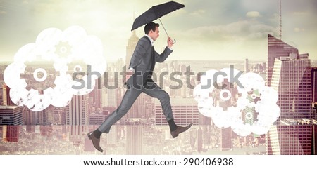 Businessman jumping holding an umbrella against room with large window looking on city