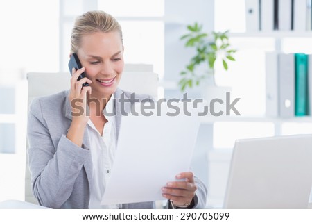 Smiling businessman phoning at her desk in her office