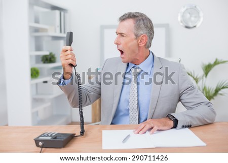 Irritated businessman answering phone in his office