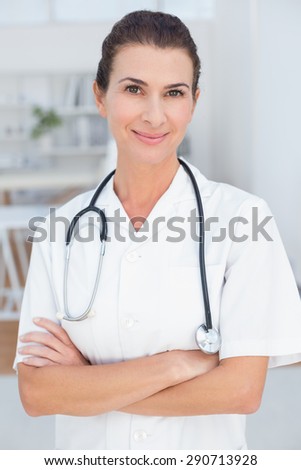Smiling doctor looking at camera with arms crossed in medical office