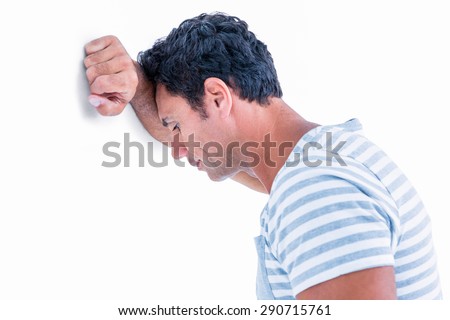 Sad man leaning his head against a wall on white background