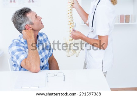 Doctor showing anatomical spine to her patient in medical office