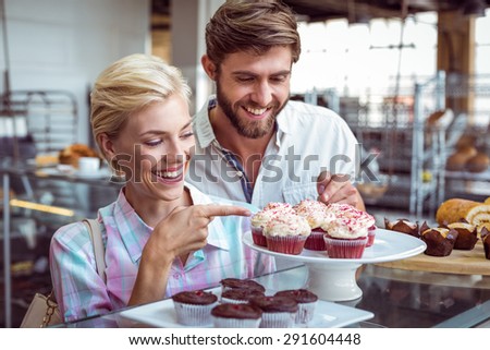 Cute couple on a date pointing chocolate cakes at the bakery