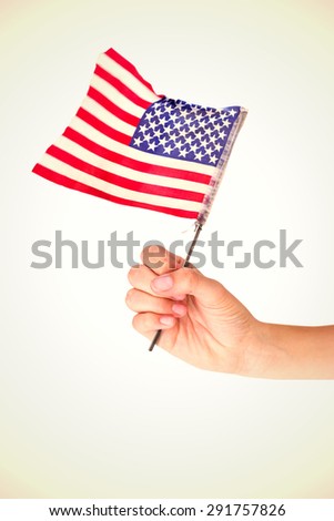 Hand waving american flag against white background with vignette