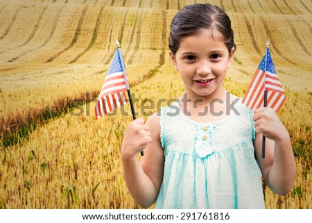 Cute girl with american flag against rural fields
