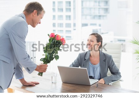 Businessman offering flowers to his colleague in an office