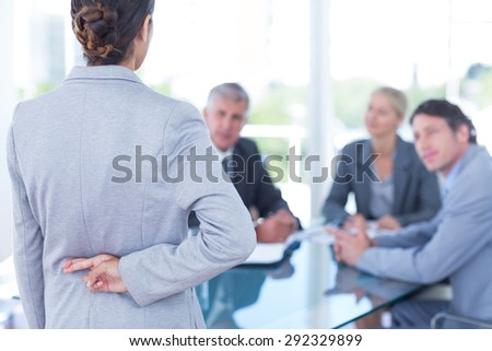 Businesswoman with fingers crossed behind her back in an office