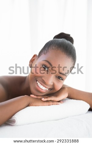 Peaceful pretty woman lying on towel smiling at camera at the health spa