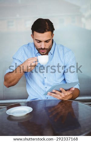 Businessman drinking coffee while watching tablet outside the cafe