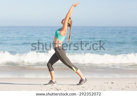 Fit woman stretching her back at the beach