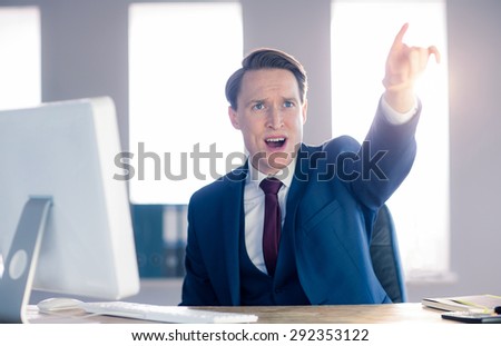 Angry businessman pointing and shouting in his office