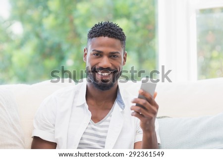 Casual man using his smartphone at home in the living room