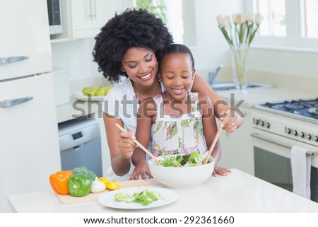 Mother and daughter making a salad together at home in the kitchen