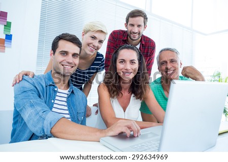 Happy creative business team using laptop in meeting at office