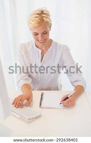 Smiling blonde woman using computer in the office