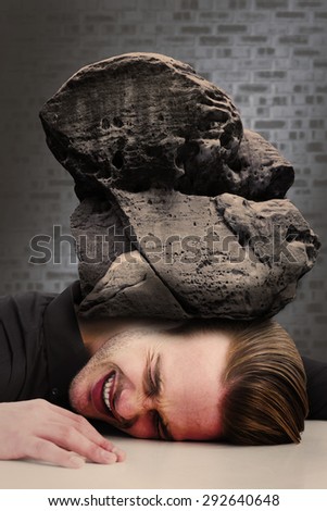 Stressed businessman banging his head against dark grey room