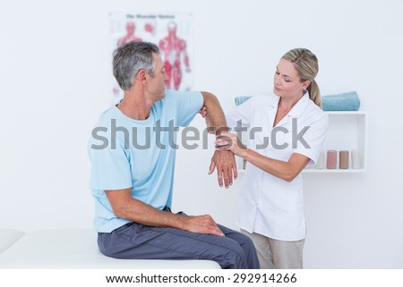 Doctor stretching a man arm in medical office