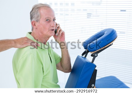 Man having back massage while talking on the phone in medical office