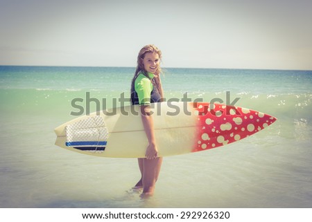 Pretty blonde woman holding surf board at the beach
