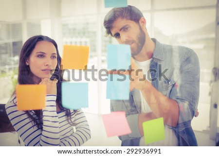 Puzzled business team looking post its on the wall in the office