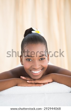 Pretty woman lying on massage table smiling at the camera at the health spa