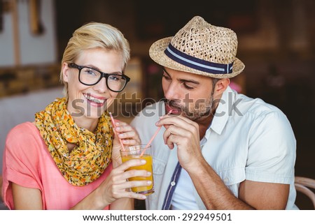 Cute couple on a date sharing an orange juice at the cafe