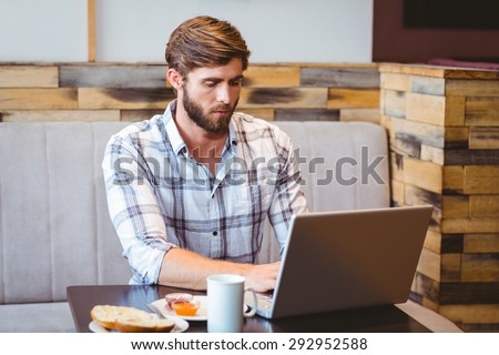 Smiling student using laptop in cafe at the university
